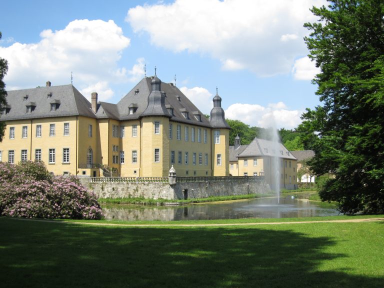 Photo of a castle in Germany, with a green lush park and a fountain