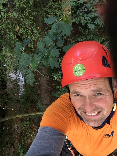 Selfie of a man with a red helmet up in a tree